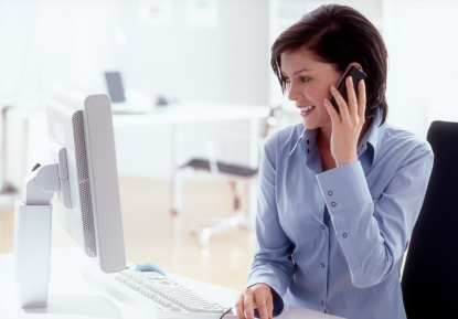 A woman talking on the phone while looking at her computer screen 