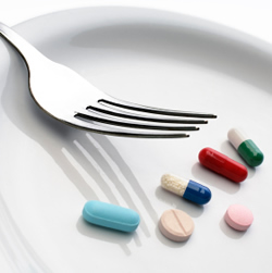 A white plate with a fork and colourful pills on it