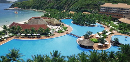 A thatched roofed holiday resort set around a huge pool; on the coast; near forested mountains 