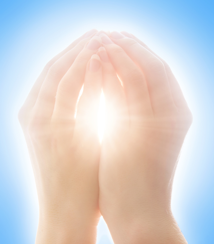 Female hands holding a ball of white light with a blue background 