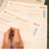image of hand with pen filling in tax forms image of hand with pen filling in tax forms